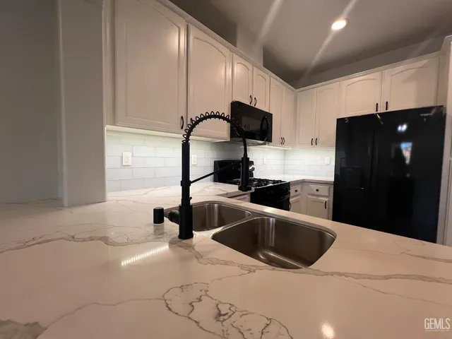 a kitchen with a sink a refrigerator and cabinets