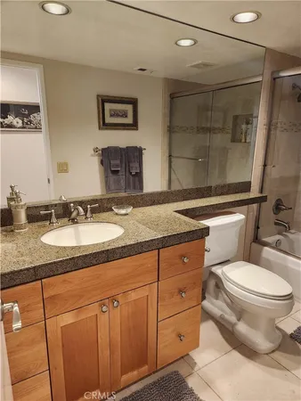 a bathroom with a granite countertop sink mirror vanity and toilet
