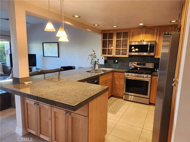 a kitchen that has a sink a microwave oven a stove and white cabinets with wooden floor