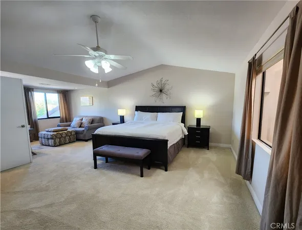 a spacious bedroom with a bed couch chandelier and a window