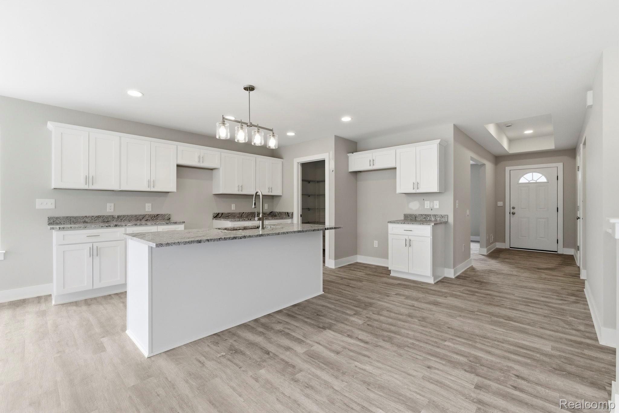 2281 Baltimore Davison, MI 48423 - Photo 7 of 26 Kitchen with white cabinets, an island with sink, light wood-style floors, dark stone countertops, and decorative light fixtures