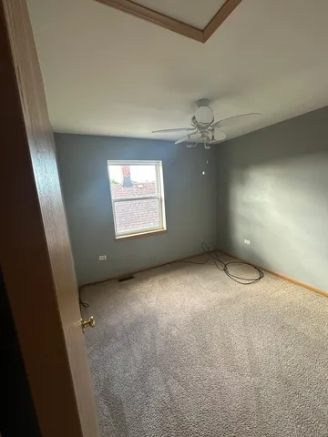 an empty room with a chandelier fan and windows
