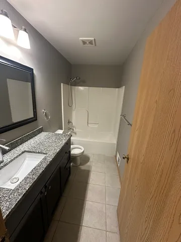 a bathroom with a granite countertop sink a toilet and a mirror