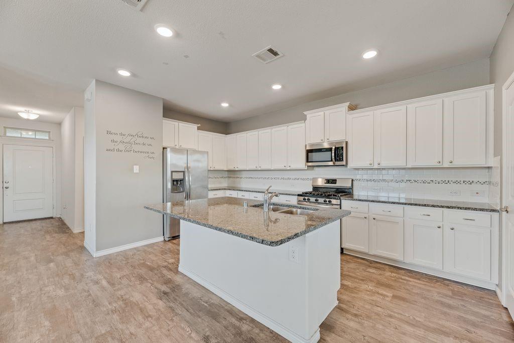 633 Bassett Hall Road Fate, TX 75189 - Photo 5 of 20 a kitchen with kitchen island granite countertop a sink and refrigerator