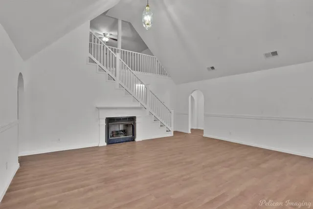 a view of empty room with stairs and wooden floor