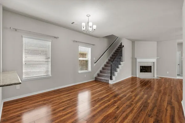 a view of an empty room with wooden floor fireplace and a window