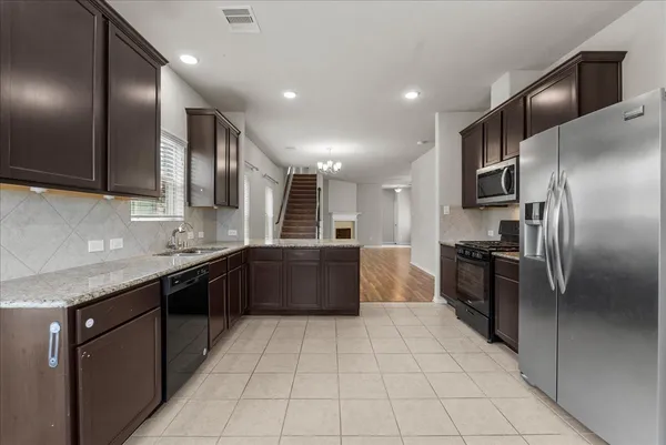 a large kitchen with stainless steel appliances granite countertop a refrigerator and a sink