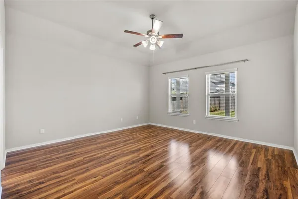 a view of an empty room with wooden floor and a window