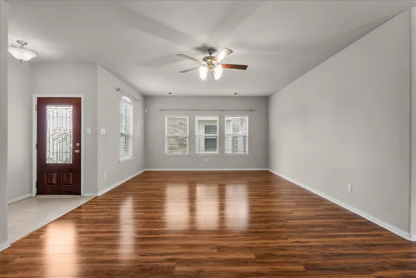 a view of an empty room with wooden floor and a window