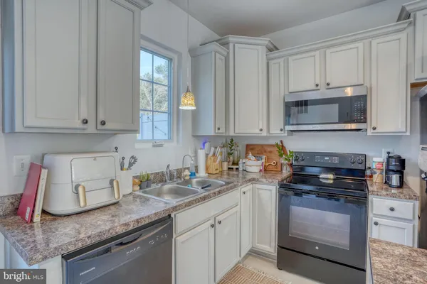 a kitchen with granite countertop white cabinets and stainless steel appliances