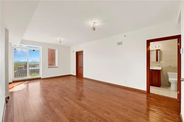 a view of an empty room with wooden floor and a window