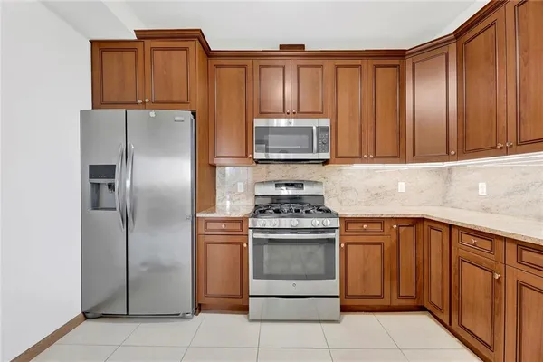 a kitchen with granite countertop stainless steel appliances a stove a refrigerator and cabinets