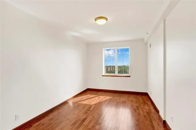 an empty room with wooden floor and window