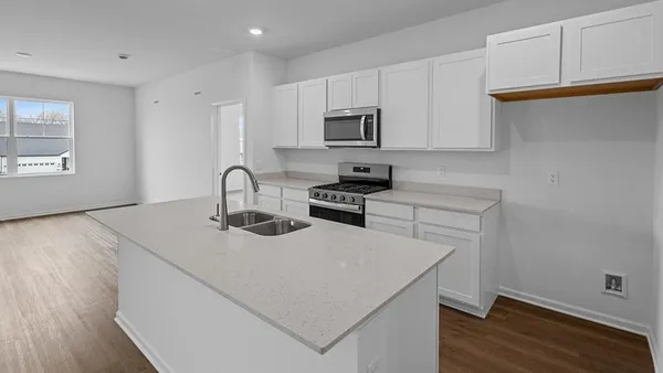 a kitchen with stainless steel appliances granite countertop a sink dishwasher a stove and a microwave with wooden floor
