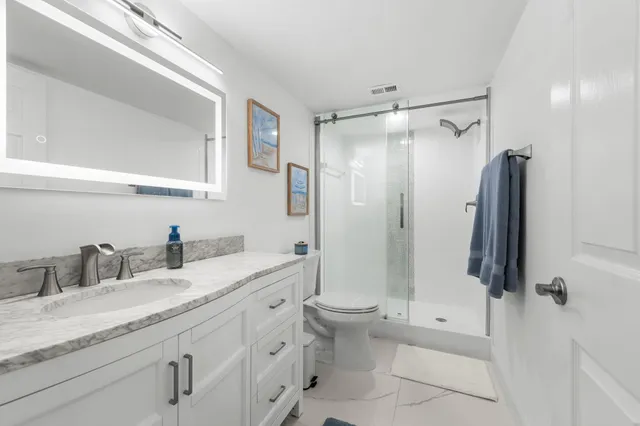 a bathroom with a granite countertop sink toilet and shower