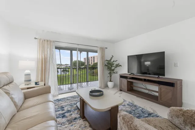 a living room with furniture a flat screen tv and a floor to ceiling window