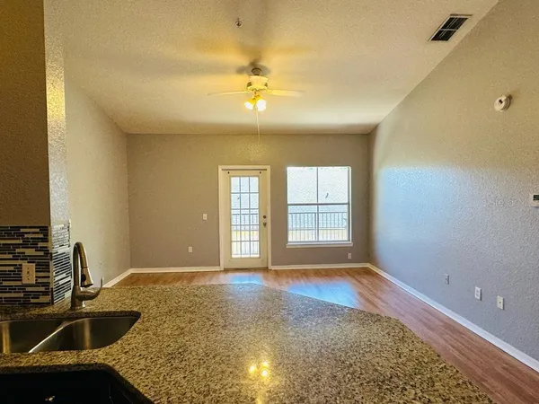 a view of an empty room with window and wooden floor