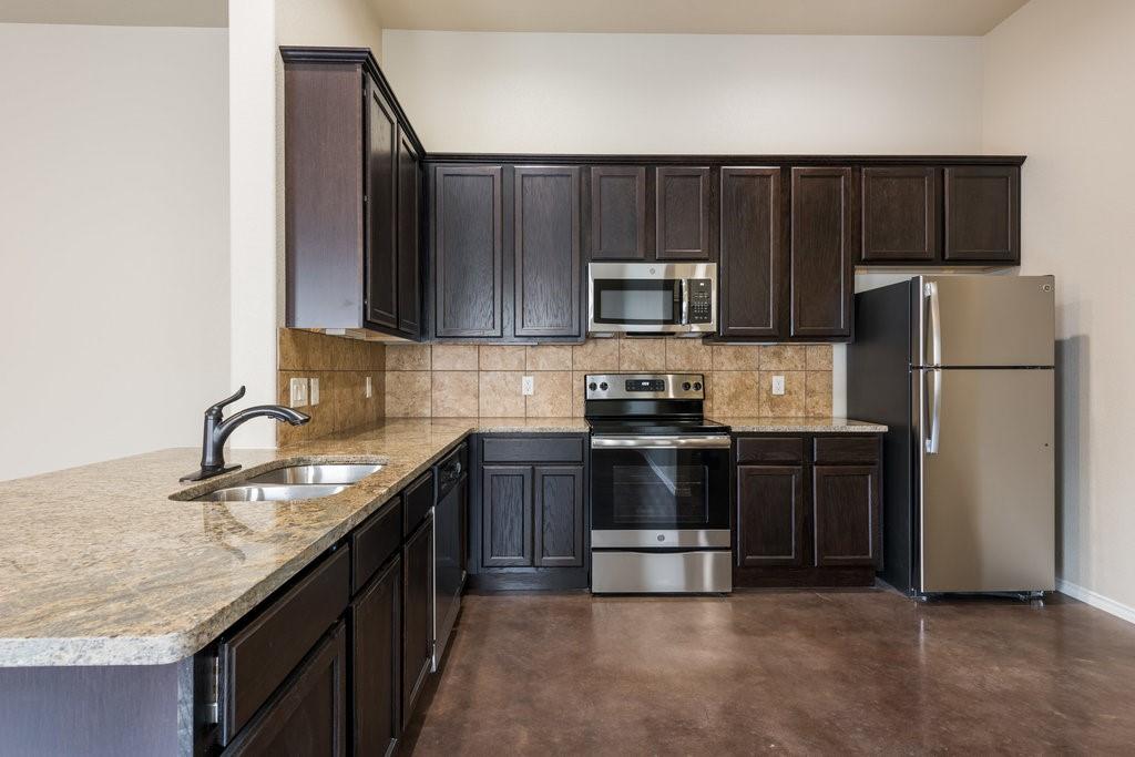 491 Jack Rabbit Lane, Unit A Buda, TX 78610 - Photo 4 of 22 A well-appointed kitchen showcasing rich cabinetry, granite countertops, and stainless steel appliances.