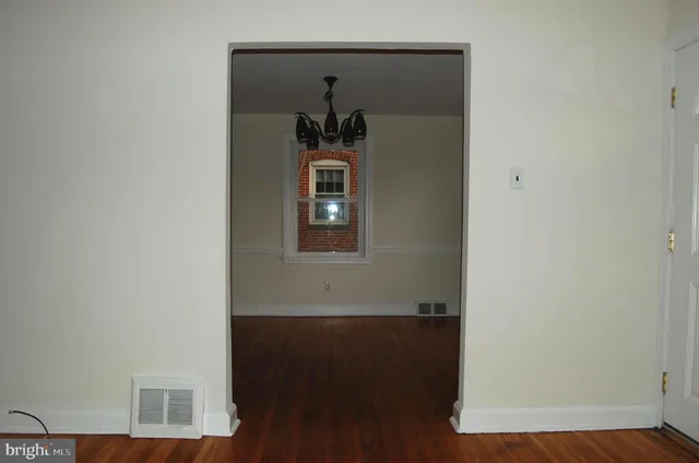 a view of a hallway with wooden floor and a cabinet