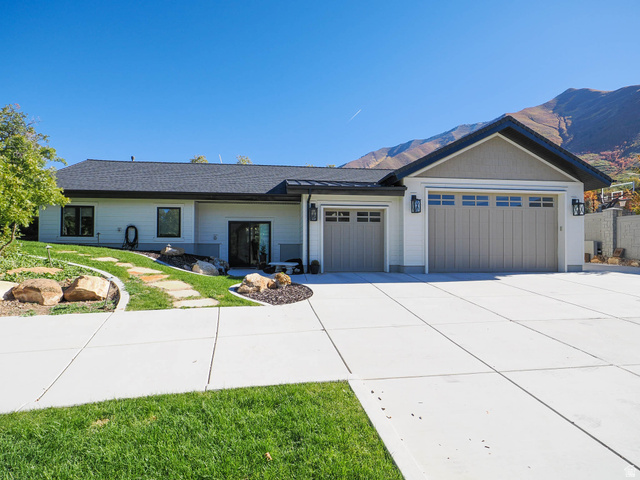 3167 South Mapleton Ests Drive Mapleton, UT 84664 - Photo 27 of 30 Contemporary exterior with white siding and dark trim, featuring a multi-car garage with panel doors, a paved driveway, and a landscaped front yard with a stone pathway
