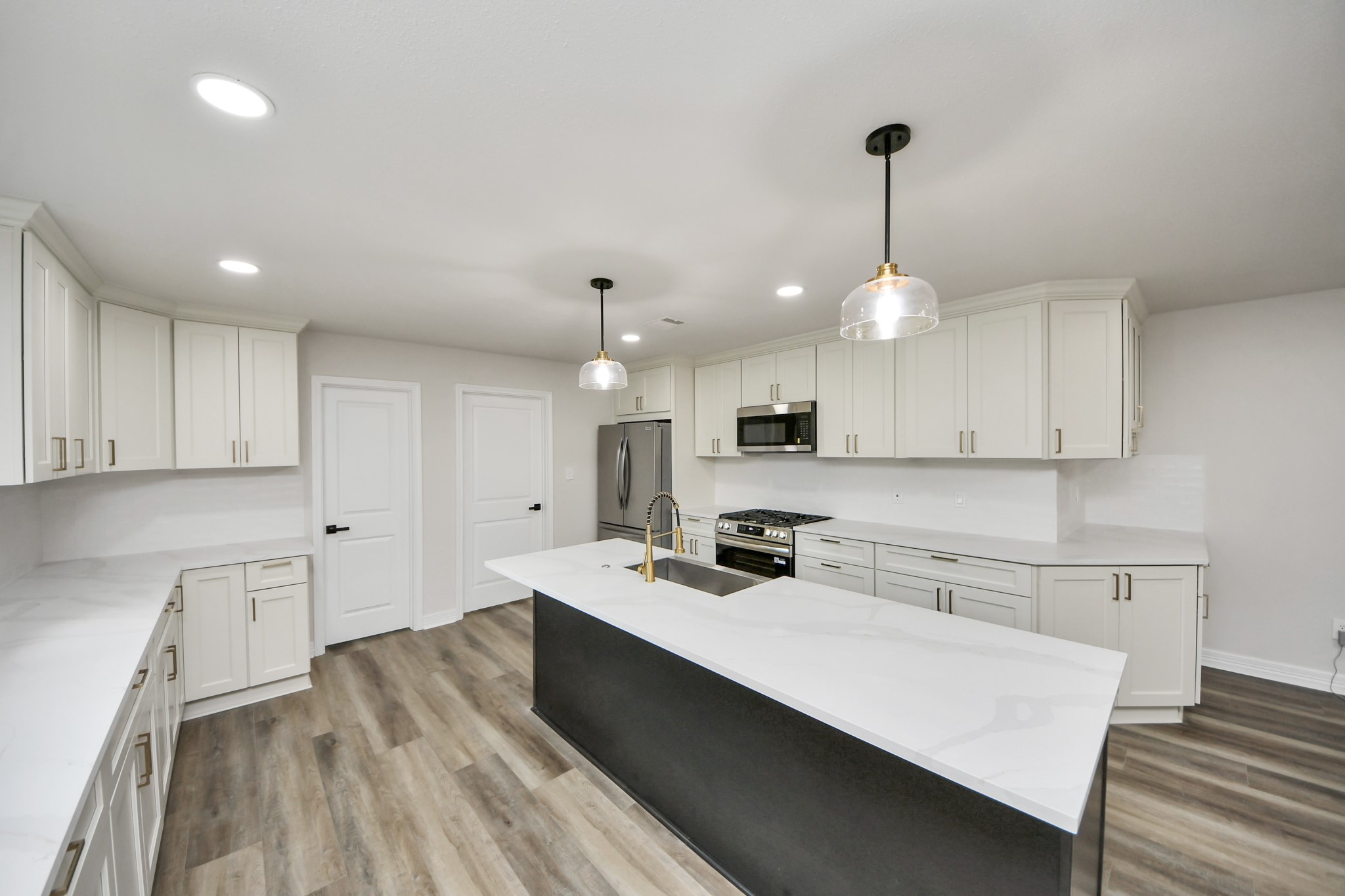 4311 Goldfinch Street Houston, TX 77035 - Photo 14 of 40 a large kitchen with kitchen island a stove a sink a refrigerator and white cabinets with wooden floor