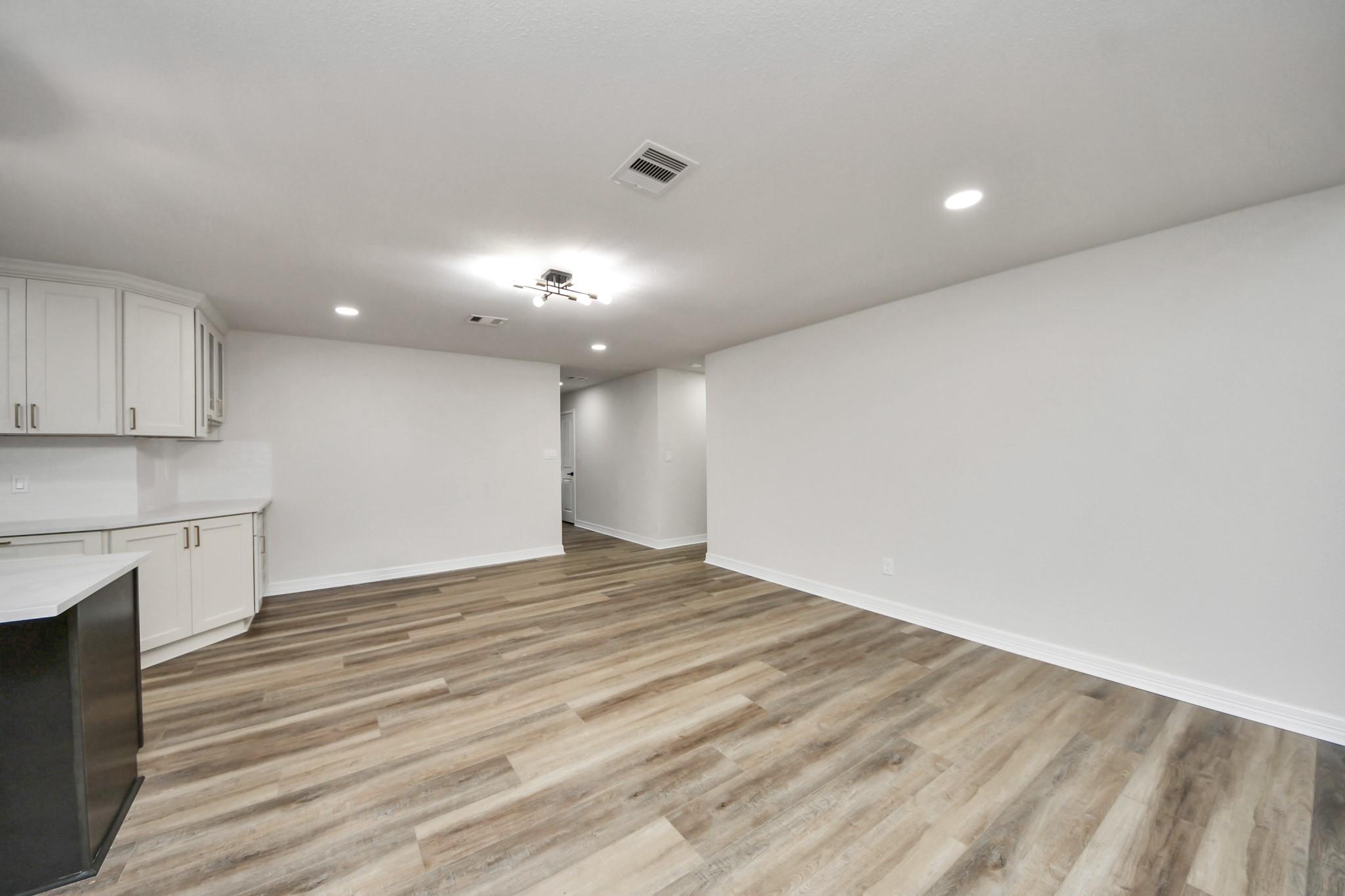 4311 Goldfinch Street Houston, TX 77035 - Photo 10 of 40 a view of an empty room with wooden floor and a kitchen