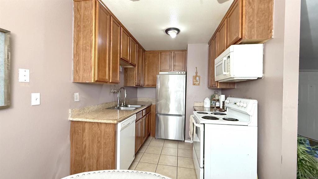 10235 Madrid Way, Unit 114 Spring Valley, CA 91977 - Photo 8 of 26 a kitchen with a refrigerator a stove a sink dishwasher and wooden cabinets