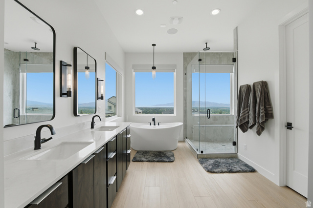 1445 Jacob Road Sandy, UT 84092 - Photo 24 of 52 Double vanity with integrated sinks, freestanding soaking tub, glass-enclosed shower, light wood-finish flooring, and contemporary pendant lighting