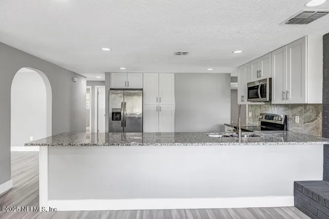a view of kitchen with granite countertop stainless steel appliances and a sink