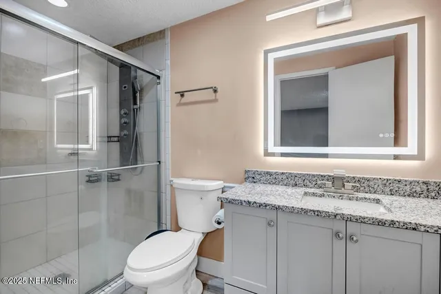a bathroom with a granite countertop sink toilet and shower
