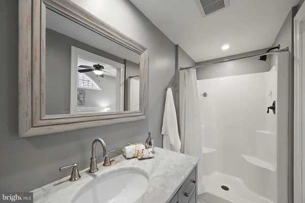 a bathroom with a granite countertop sink a mirror and shower