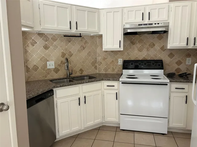 a kitchen with granite countertop white cabinets and white appliances