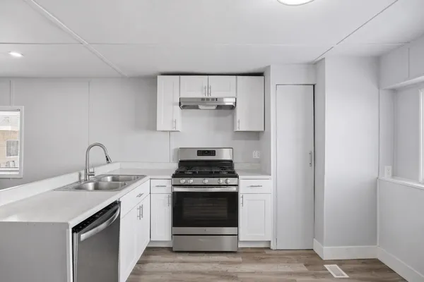 a kitchen with stainless steel appliances a stove and white cabinets