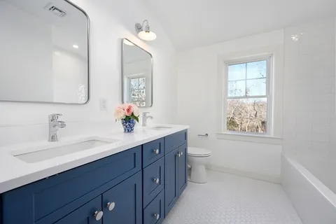 a bathroom with a double vanity sink toilet and a mirror