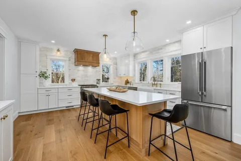 a kitchen with stainless steel appliances granite countertop a sink a stove a refrigerator and island with wooden floor