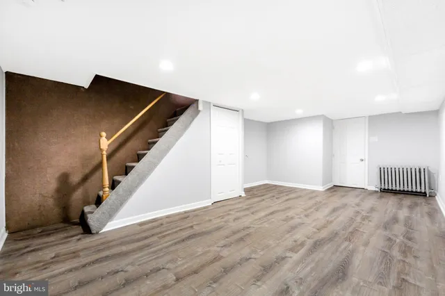 a view of an empty room with wooden floor and stairs