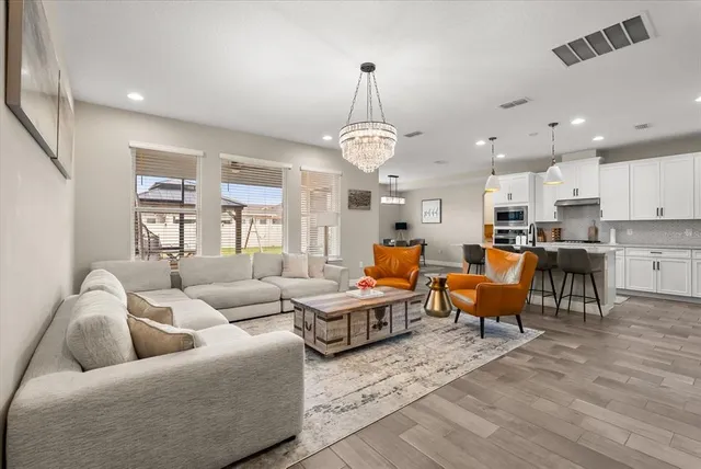 a kitchen with stainless steel appliances granite countertop a sink a stove a refrigerator cabinets and chairs