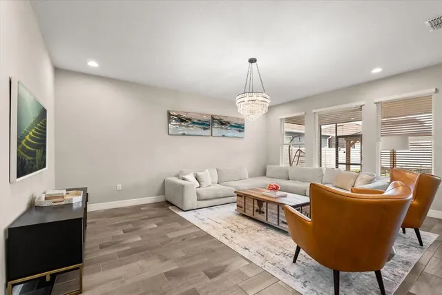 a living room with furniture kitchen view and a chandelier