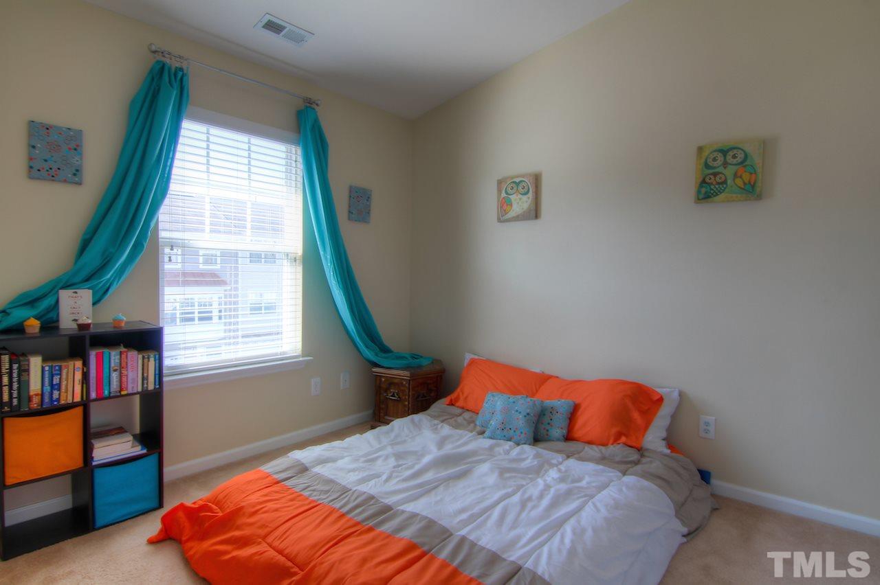 115 Darley Dale Loop Apex, NC 27502 - Photo 16 of 25 a bedroom with a bed and a book shelf
