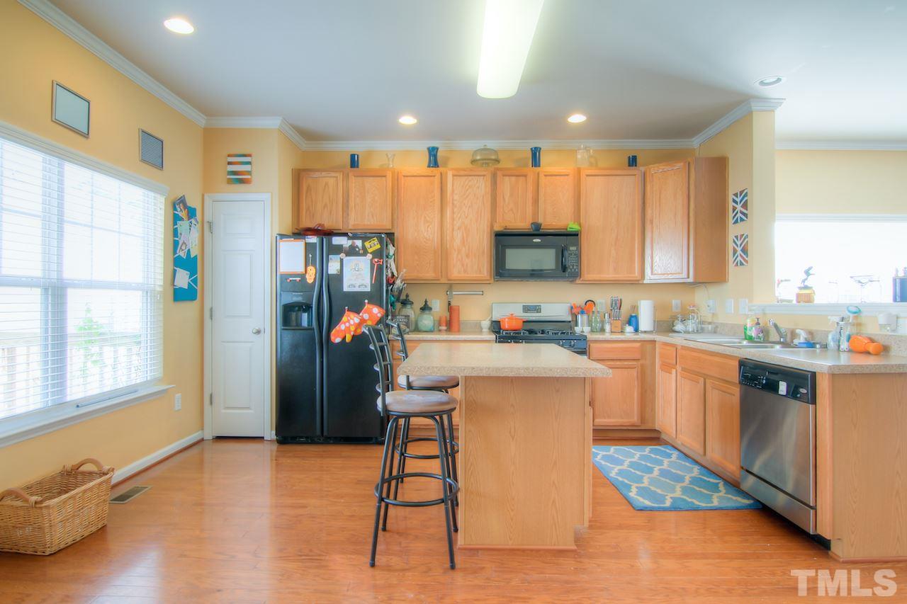 115 Darley Dale Loop Apex, NC 27502 - Photo 5 of 25 a kitchen with stainless steel appliances granite countertop a refrigerator sink and cabinets