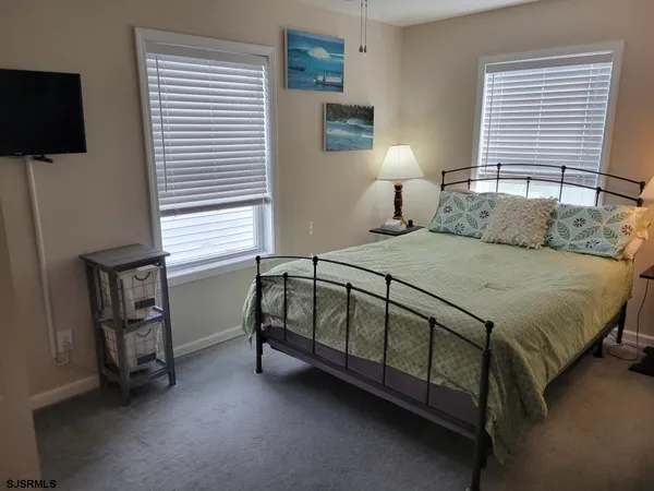 a bedroom with a bed a flat screen tv and a window