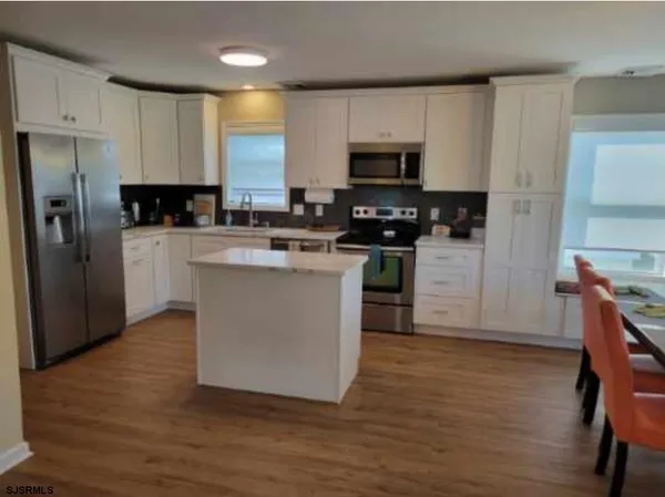 a kitchen with stainless steel appliances granite countertop a stove top oven a refrigerator a sink and dishwasher with wooden floor