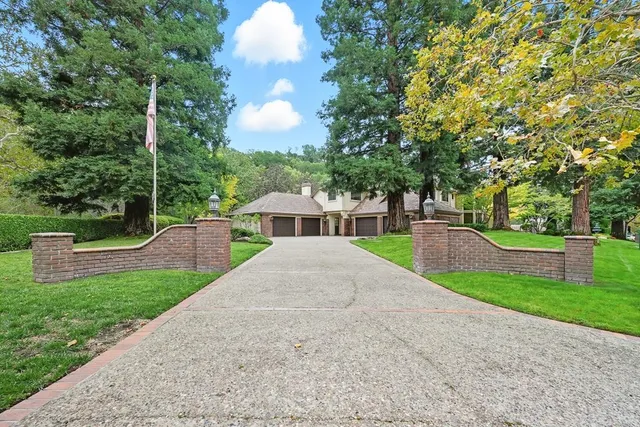 a view of a house with a yard and a large tree