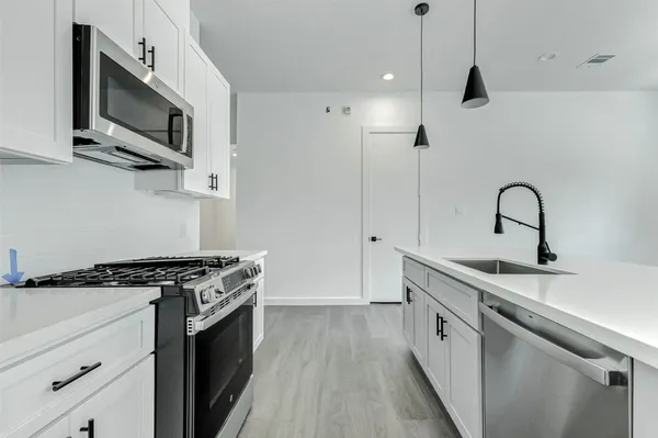 a kitchen with stainless steel appliances a sink dishwasher a stove and a microwave oven with wooden floor