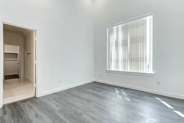 a view of an empty room with wooden floor and closet