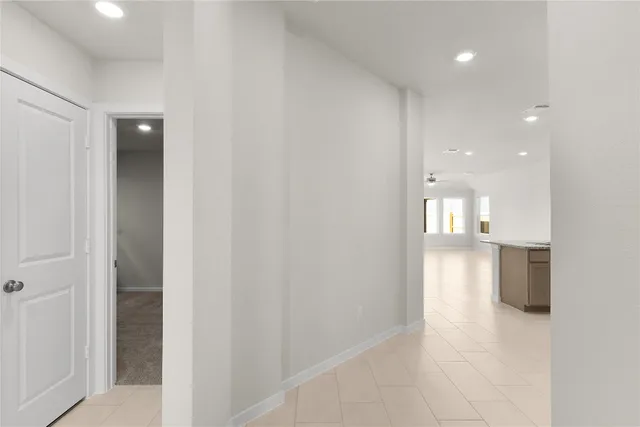 a view of an empty room with a ceiling fan and kitchen space