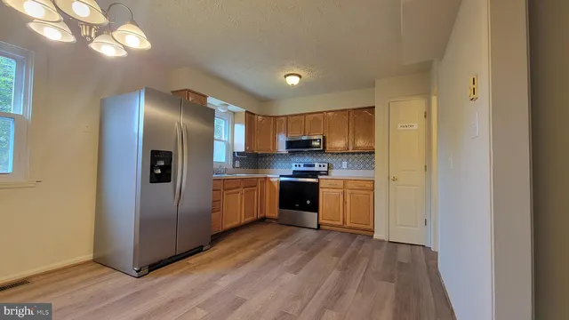 a kitchen with stainless steel appliances granite countertop a refrigerator a sink dishwasher a stove with wooden floor and cabinets