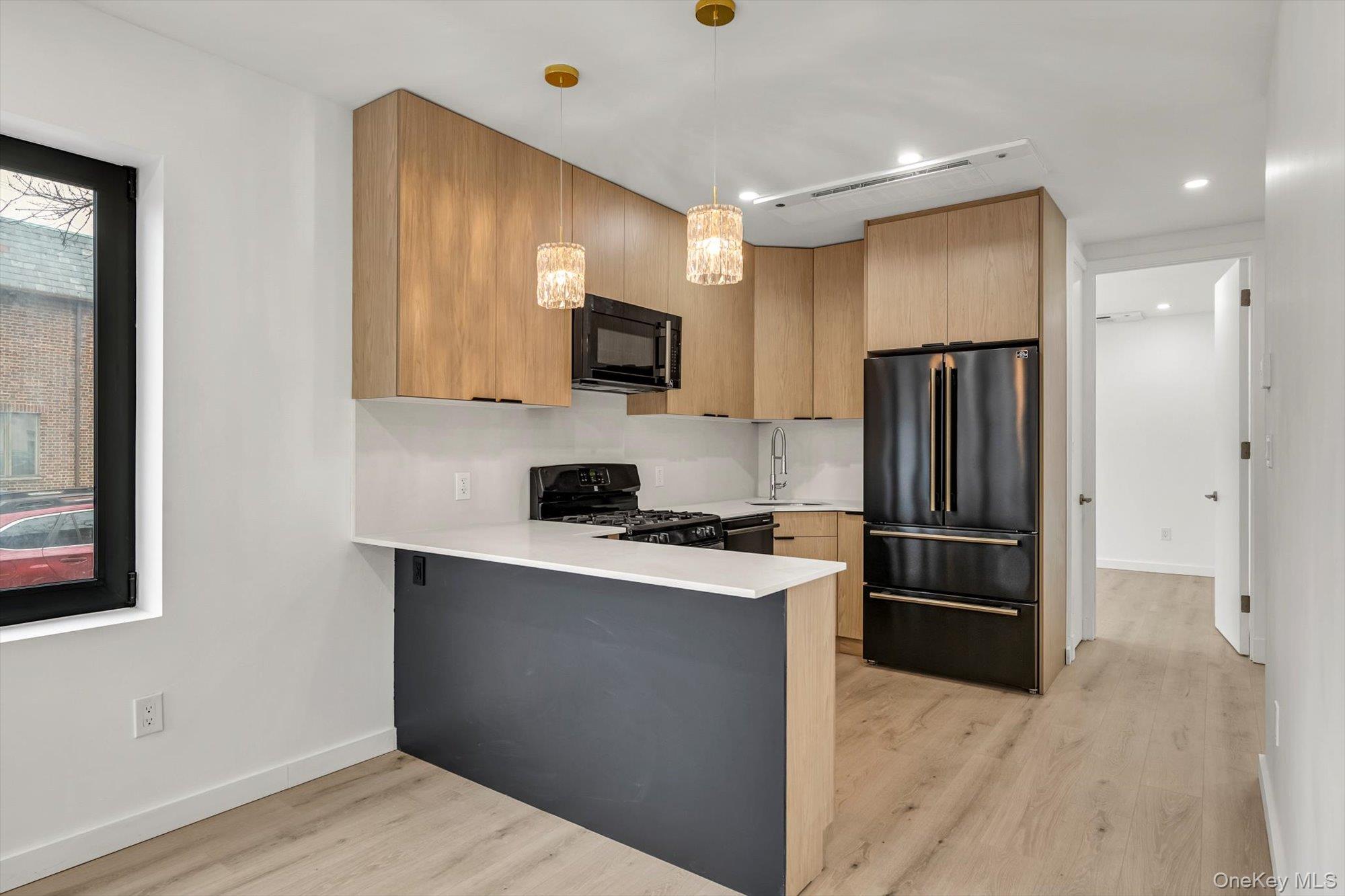 85-45 67th Road Queens, NY 11374 - Photo 6 of 28 a kitchen with a refrigerator a microwave a sink and cabinets
