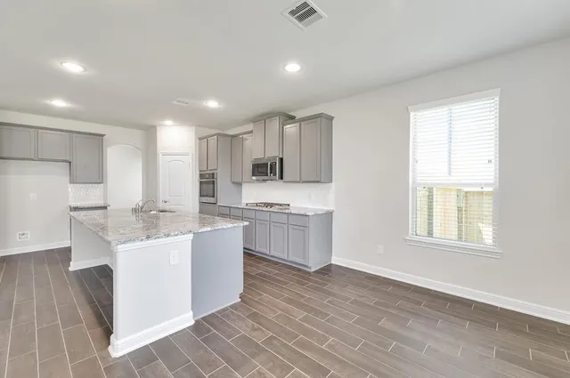 an empty room with wooden floor fireplace and windows
