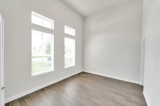 an empty room with wooden floor and windows